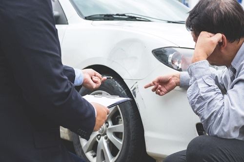 Man and insurer inspecting car accident damage